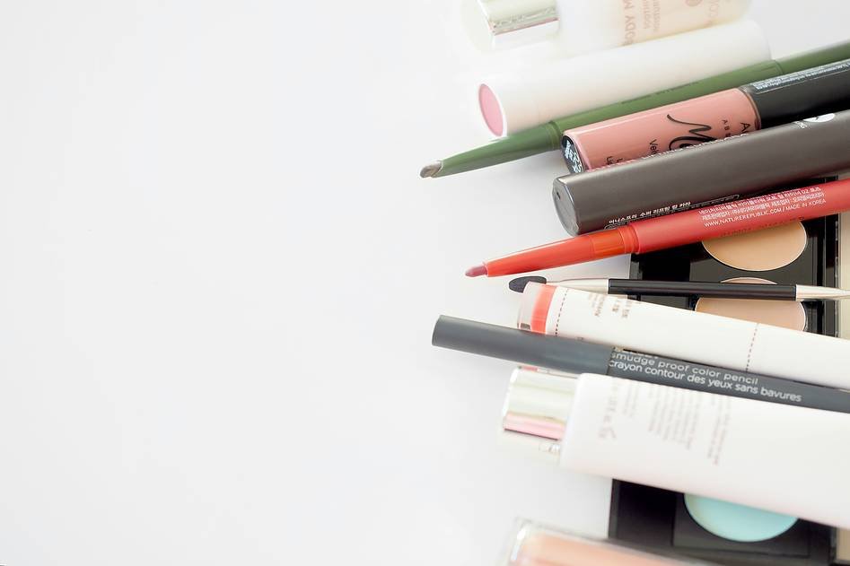 Assortment of lip pencils in various shades arranged on a vanity table with makeup brushes